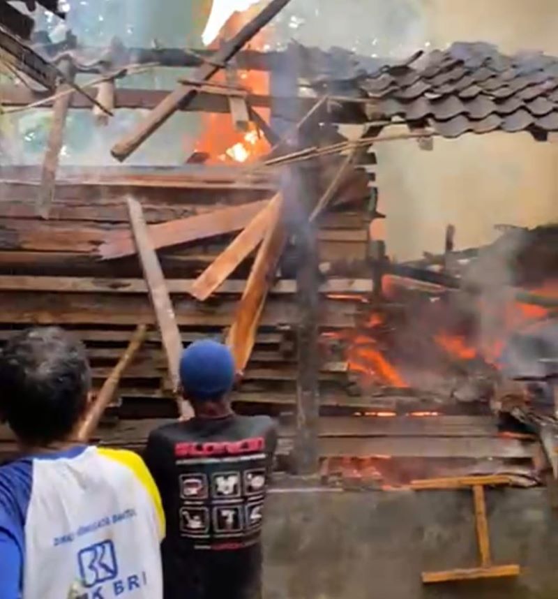 Petugas sedang memadamkan api yang membakar gudang kayu