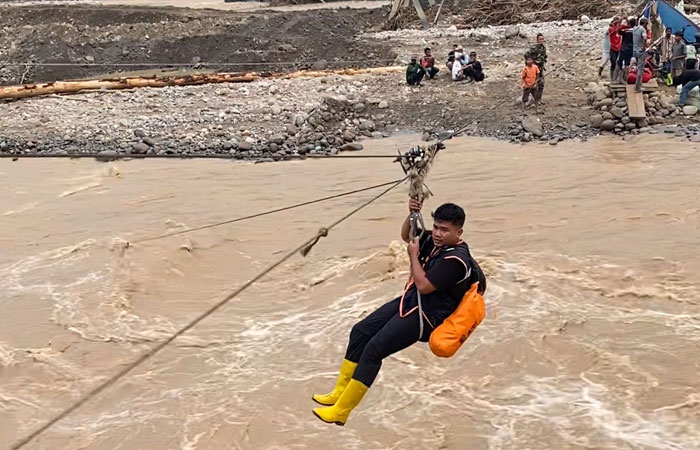 BERGELANTUNGAN: Para relawan saat menyeberang Sungai Berawang Gajah harus menggunakan tali keling, karena jembatan sebagai akses utama raib tersapu banjir.