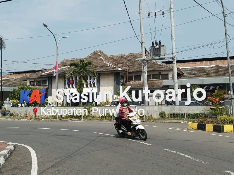 PAPAN PENANDA: Penumpang kereta api yang baru menyelesaikan perjalanan tiba di Stasiun Kutoarjo.