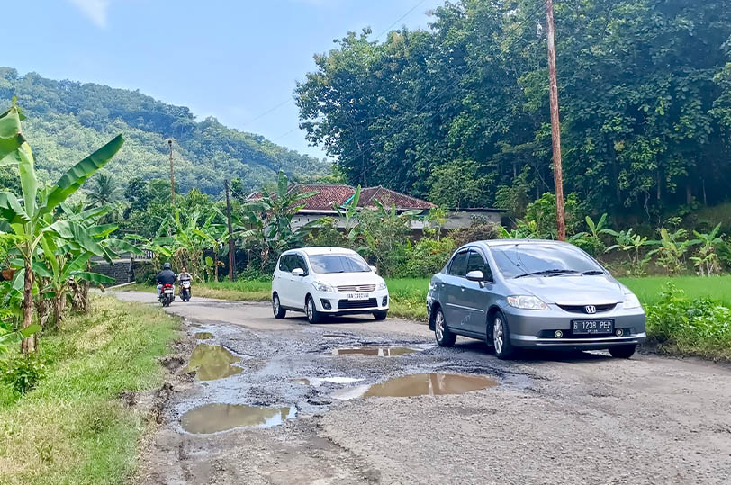 JALAN BERLUBANG: Pengguna jalan yang melintas menuju wisata PAP Krakal terpantau memperlambat laju kendaraan akibat kondisi jalan rusak.