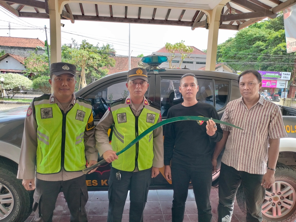 Personel Polsek Karanganyar memegang senjata tajam jenis klewang yang ditemukan dari tangan pelajar yang hendak tawuran. (Dokumentasi Polres Kebumen)