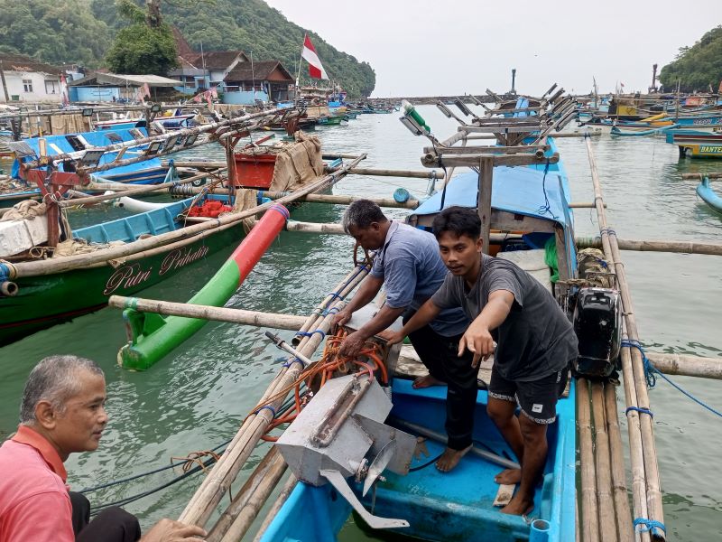 LEBIH IRIT: Dua nelayan sedang mencoba mesin listrik yang digunakan sebagai penggerak kapal di Pantai Sadeng, Jumat (30/1). Kecepatannya sama dengan mesin BBM.