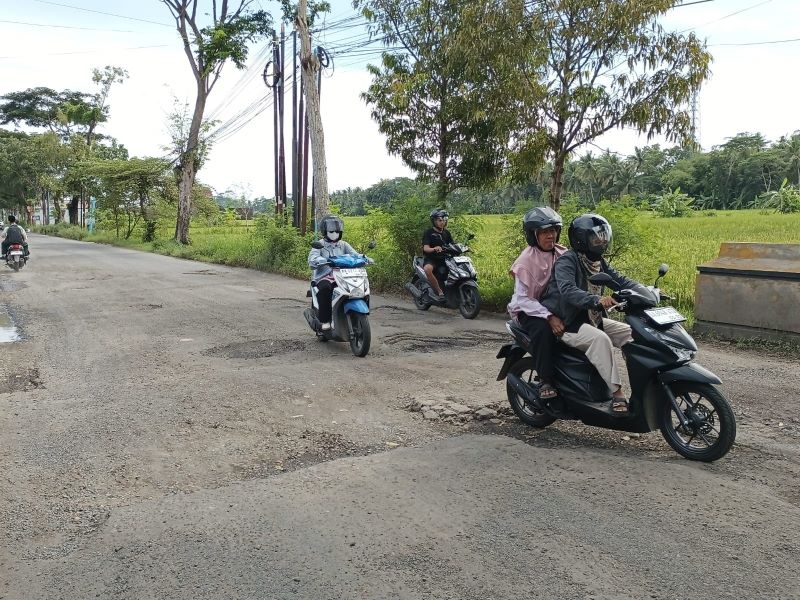 BUTUH PENANGANAN: Pengendara sepeda motor yang melintasi Jalan Kejayan terpaksa memperlambat laju kendaraan akibat kondisi jalan rusak parah.