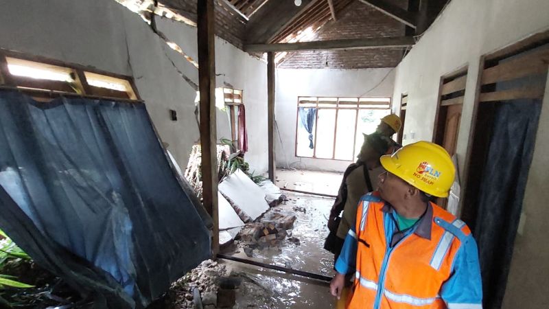 AMBROL: Personel Tanggap Bencana mengecek tembok rumah yang dihantam material longsor.&nbsp;
