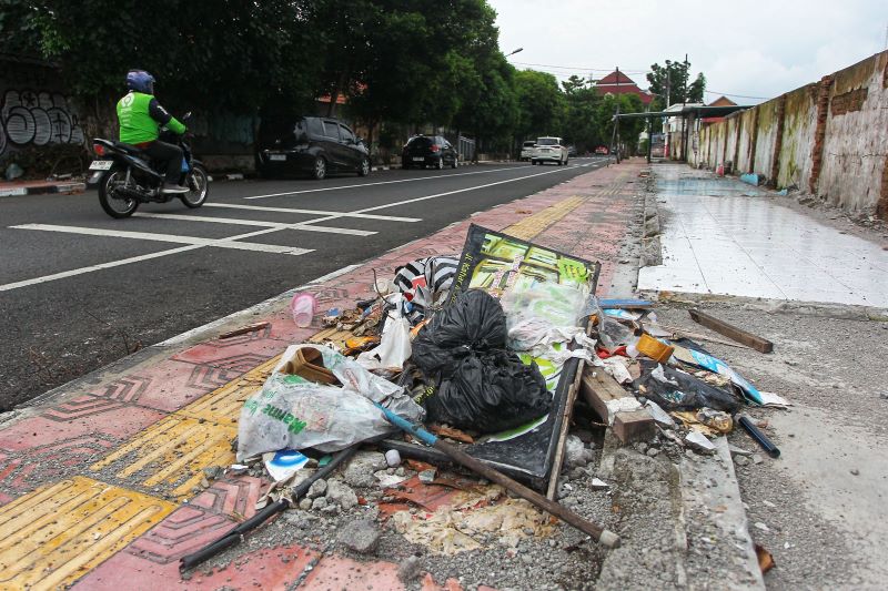 Pengguna jalan melintas di dekat tumpukan sampah yang dibuang secara liar di trotoar Jalan Kahar Muzakir, Kota Jogja Minggu (22/2).    