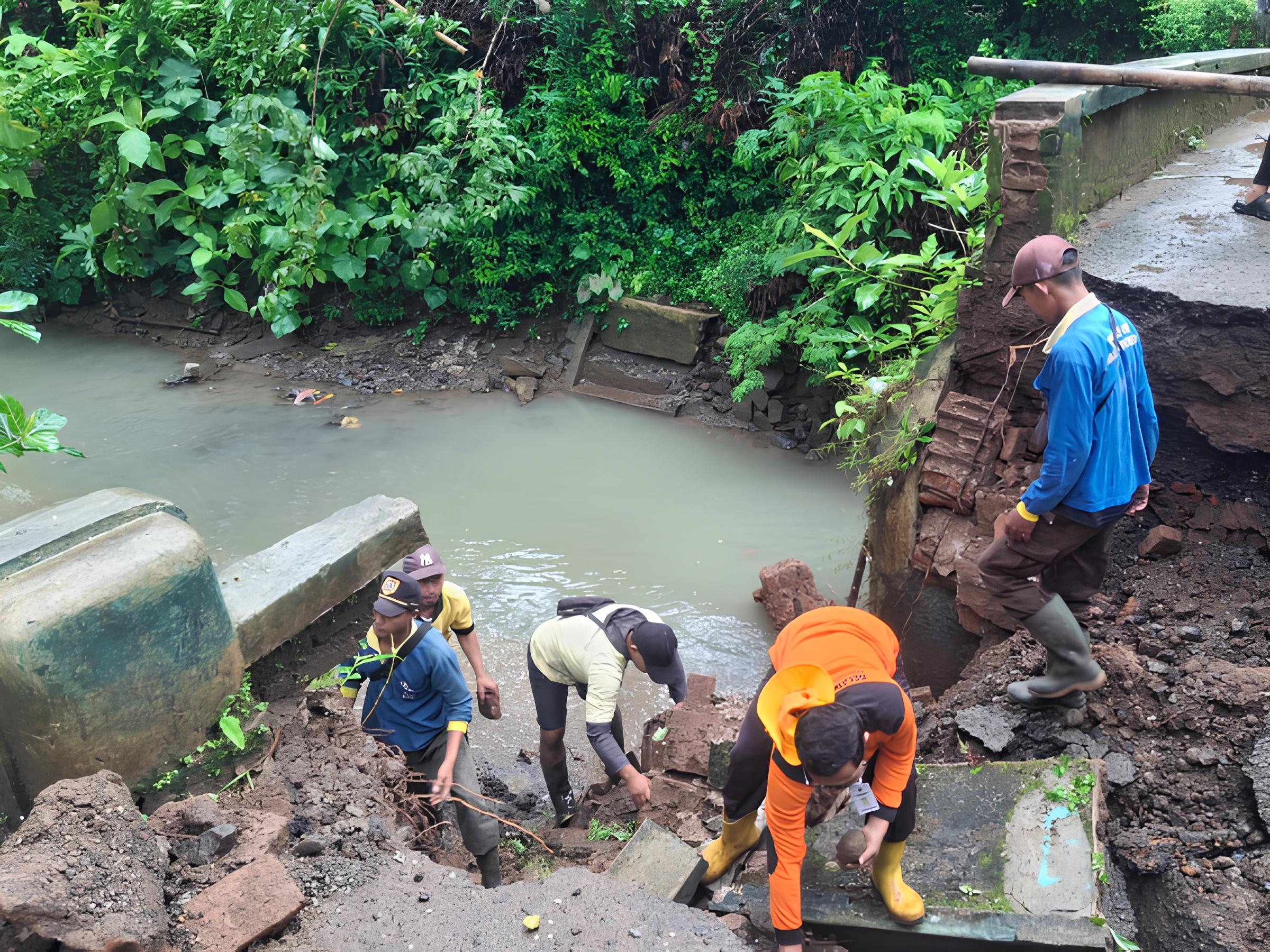 Petugas bersama warga gotong-royong membersihkan puing material jembatan Desa Pekuncen yang ambruk.(Dokumentasi Polres Kebumen)