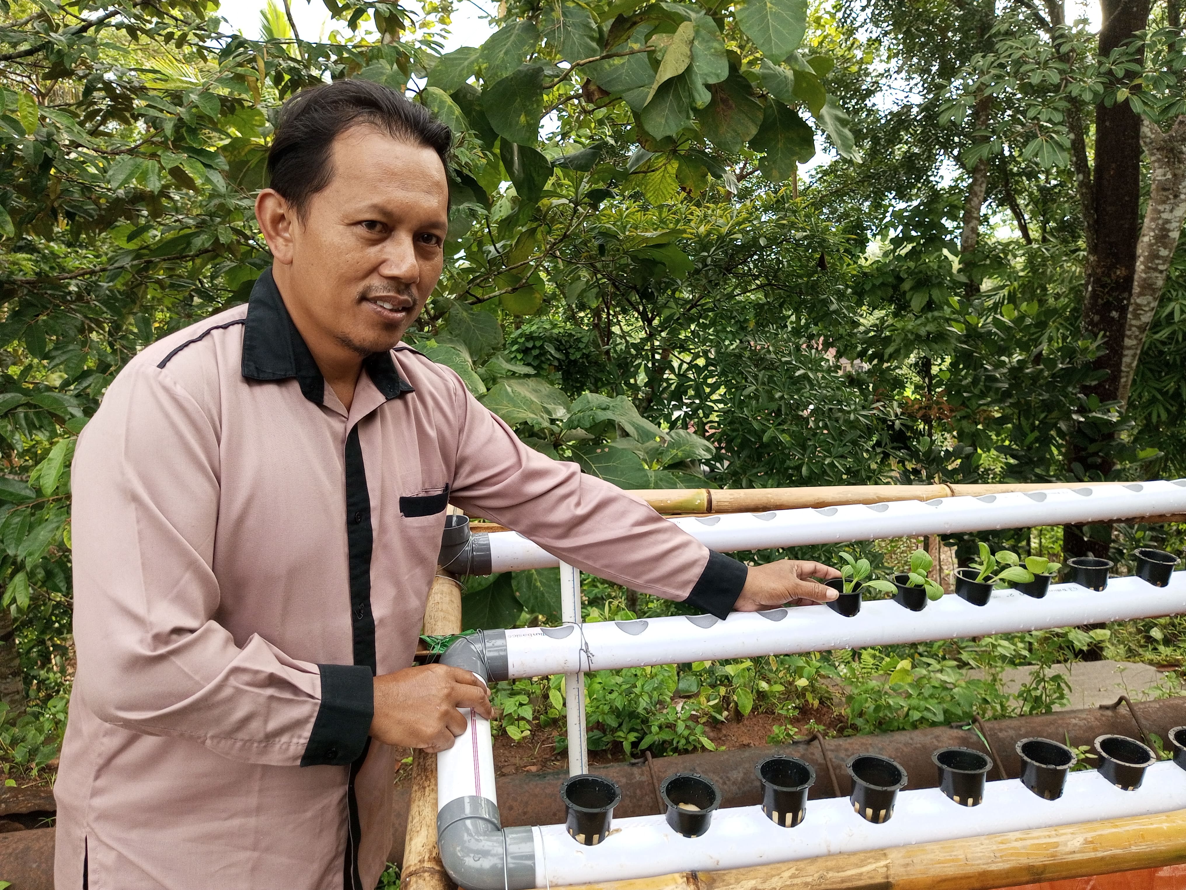 Suroso sedang menghampiri mahasiswa di instalasi hidroponik. Ia tertarik merawatnya agar tahu bagaimana siklus pertanian dengan sistem hidroponik. 