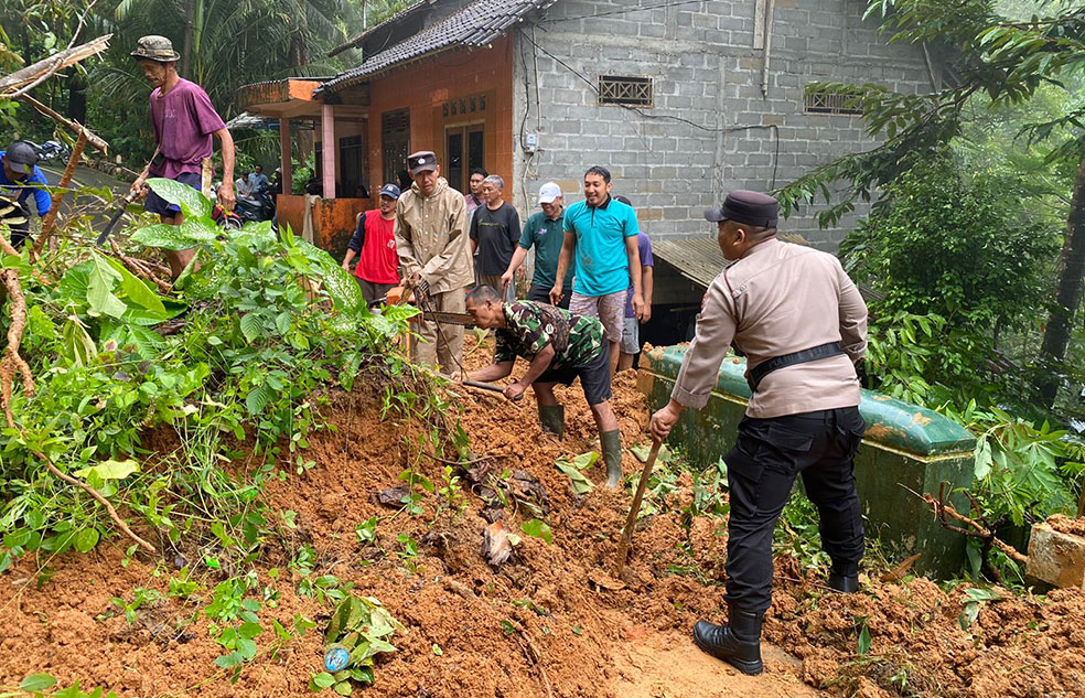Warga dan aparat kepolisian saat kerja bakti membersihkan tanah longsor di Kapanewon Kokap, Kulon Progo.