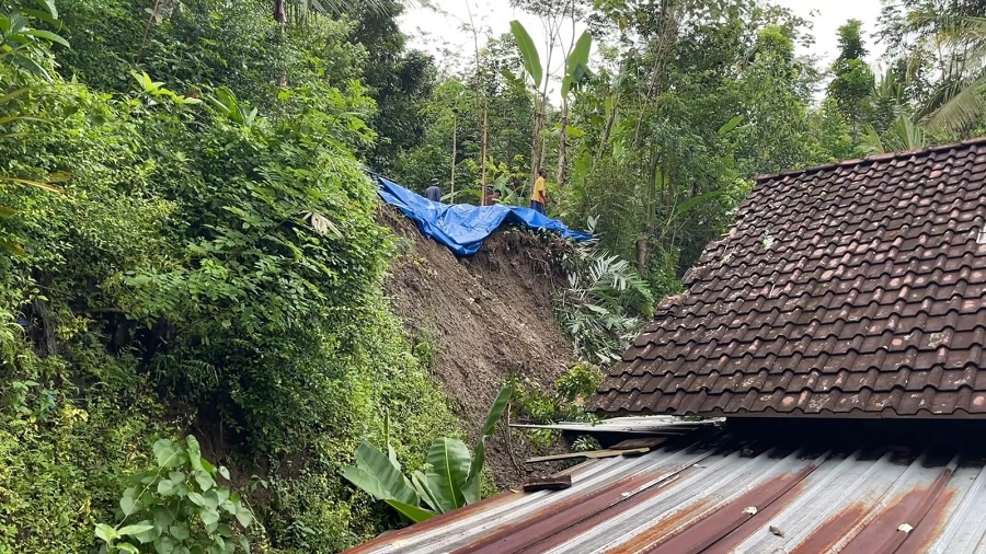 EVAKUASI: Warga bergotongroyong membersihkan area rumah dari material longsor.