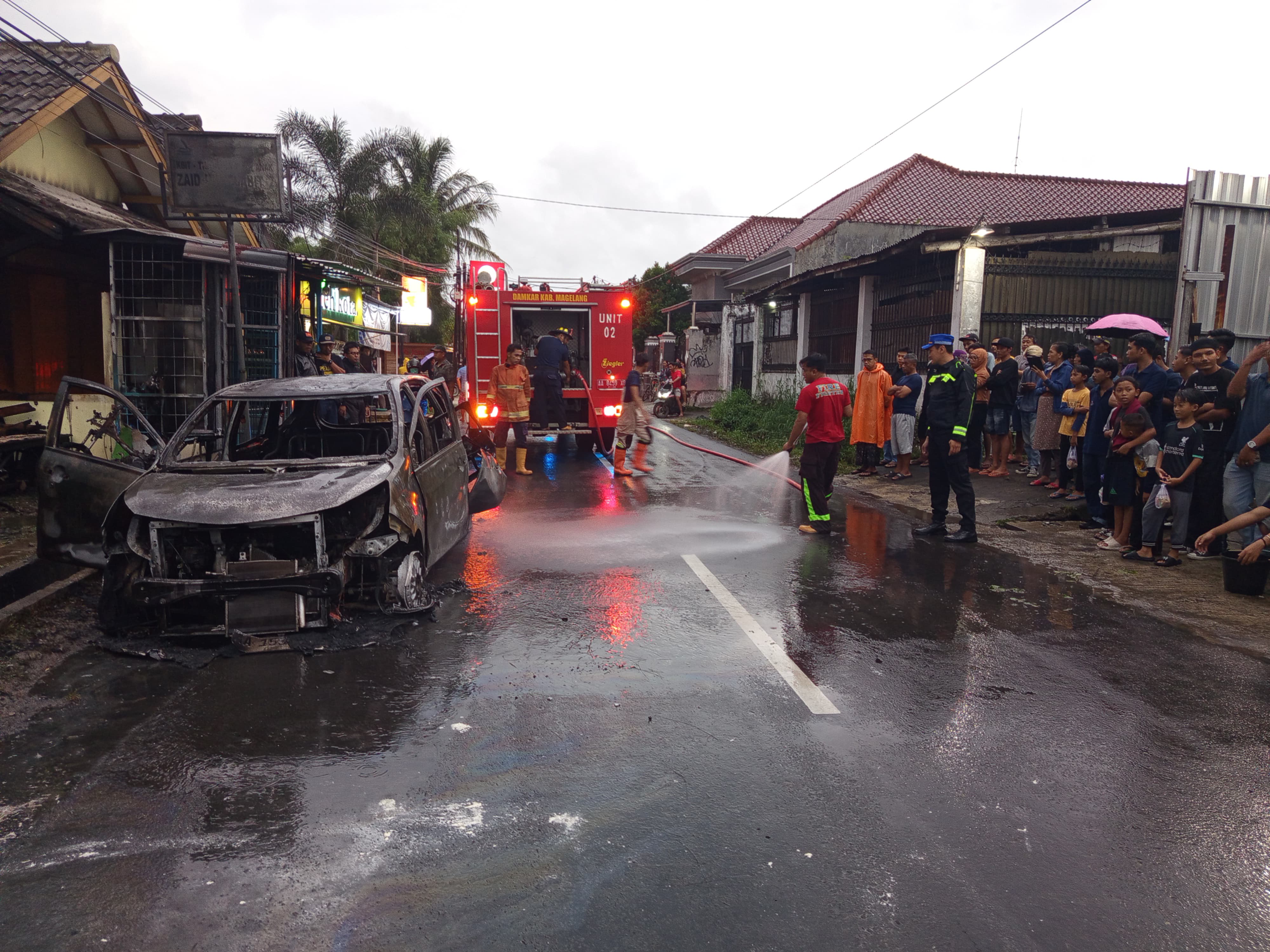 Petugas berupaya memadamkan api yang membakar sebuah mobil di Dusun Saragan, Banyurojo, Mertoyudan, Selasa sore (3/3). 