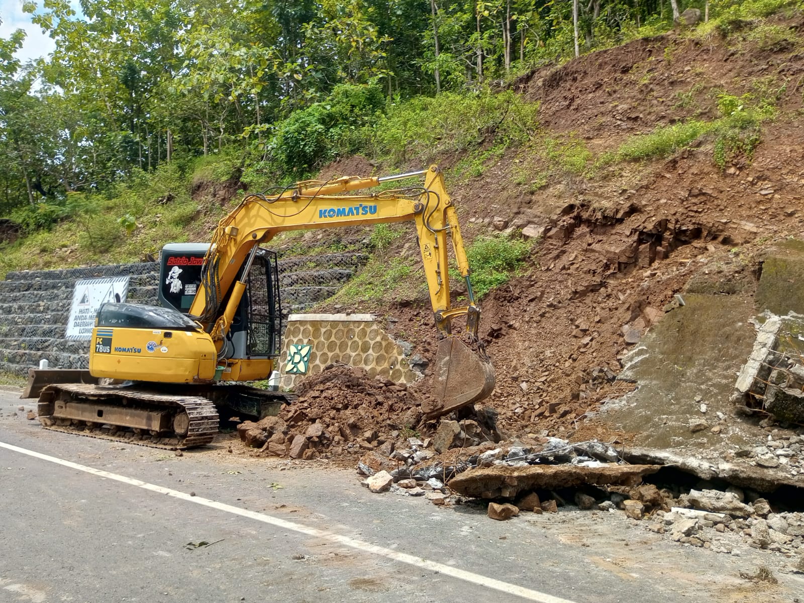 Pembersihan material longsoran di jalur tanjakan Clongop menggunakan alat berat.
