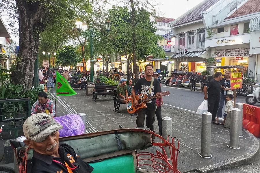 Pengamen liar menghibur sekaligus meminta uang kepada pengunjung di kawasan Malioboro, Kota Jogja, Senin (9/3/2026). 