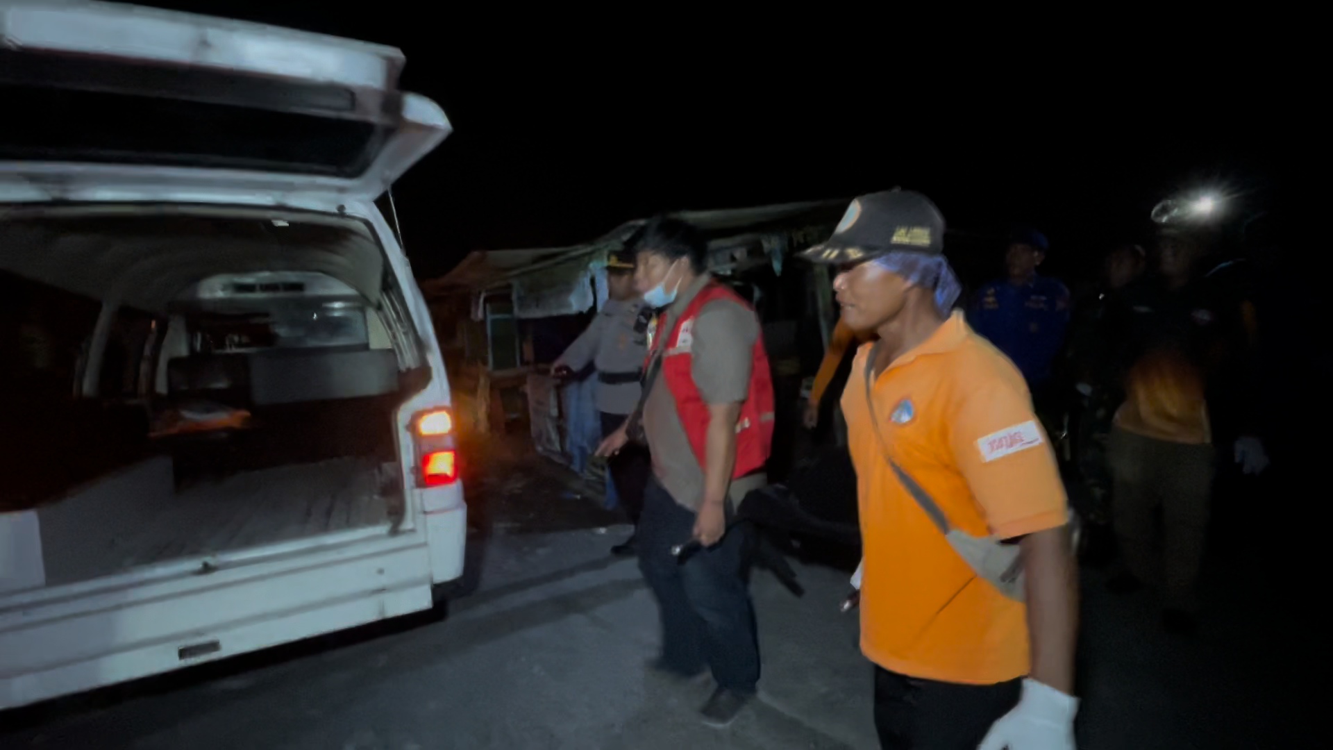 Personel gabungan mengangkat jenazah melewati pemecah ombak ke mobil pengantar.