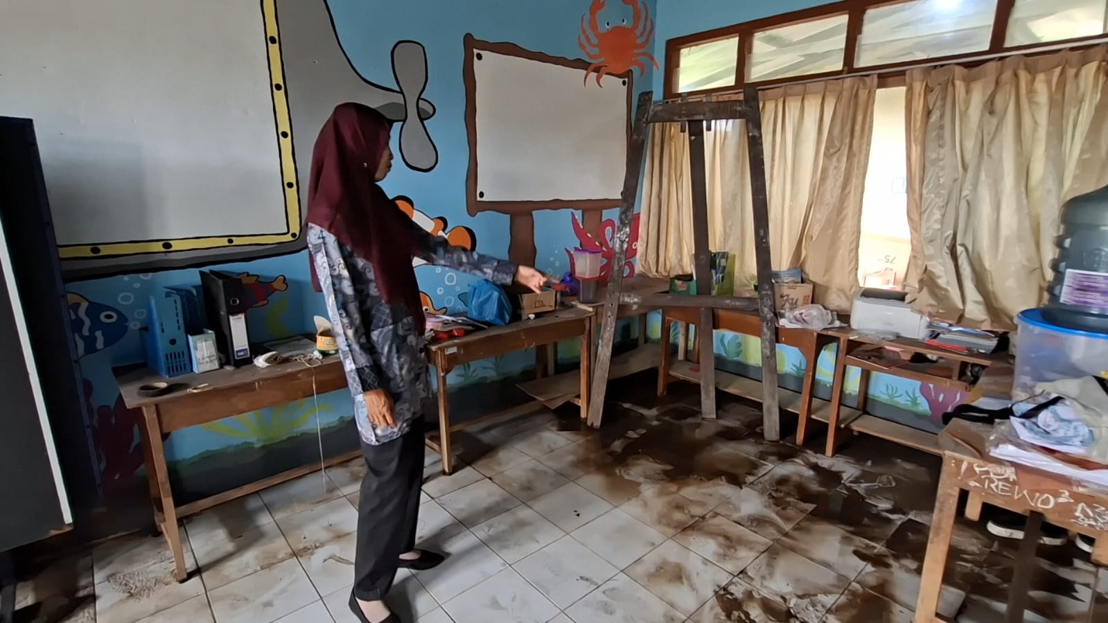 Guru SDN Degung menunjukkan batas air yang memasuki kelas saat banjir melanda.  