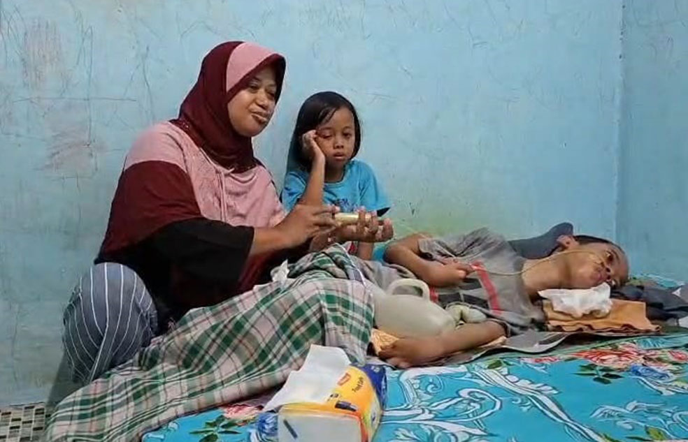 SEMANGAT: Ria menyuntikkan susu formula ke anaknya yang tak bisa bergerak kembali akibat gigitan ular berbisa.