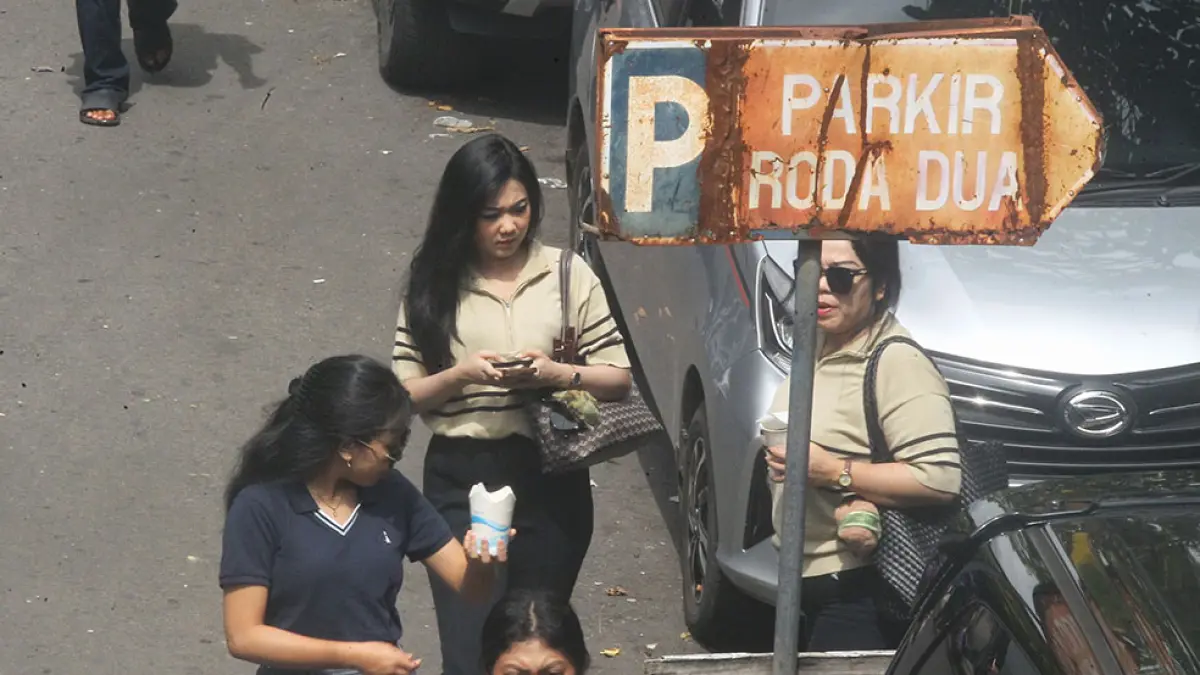 DISERBU WISATAWAN: Wisatawan melintas disirip kawasan Malioboro yang dijadikan lokasi parkir kendaraan, kemarin (27/3). Lonjakan wisatawan saat libur Lebaran memicu pelanggaran parkir di Kota Jogja. GUNTUR AGA/RADAR JOGJA