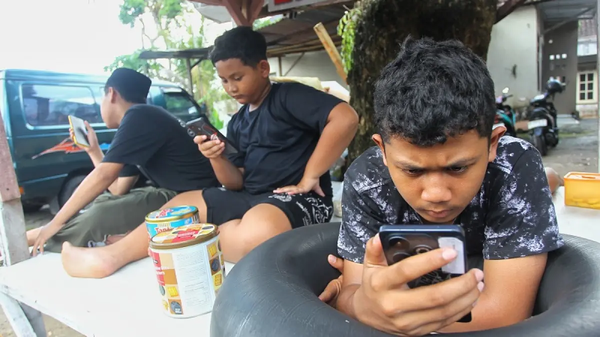 Anak-anak mengakses media sosial menggunakan telepon genggam di Saragan, Pandowoharjo, Sleman, Minggu (29/3/2026). (Guntur Aga Tirtana/Radar Jogja)
