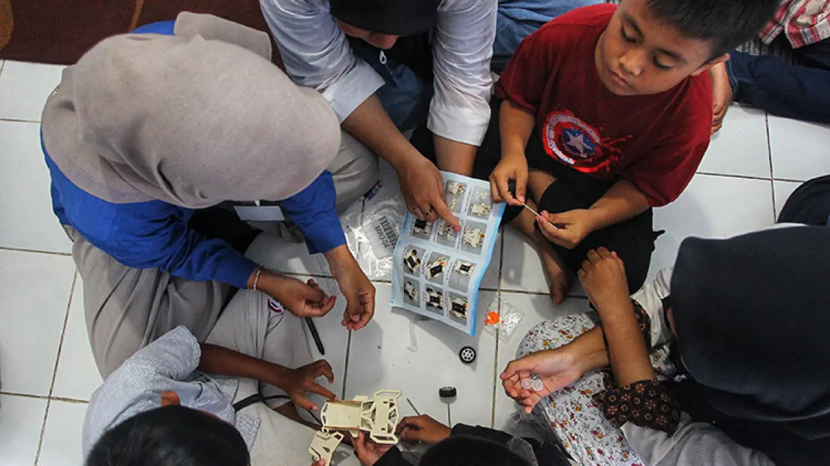 LEBIH BERVARIASI: Sejumlah relawan Amgala Foundation mendampingi anak-anak mempelajari keterampilan sains dalam Program Jam Belajar Masyarakat (JBM) di Rumah Baca Raden Mas Suryowinoto, Giwangan, Umbulharjo, Kota Jogja, Minggu (29/3/2026). 