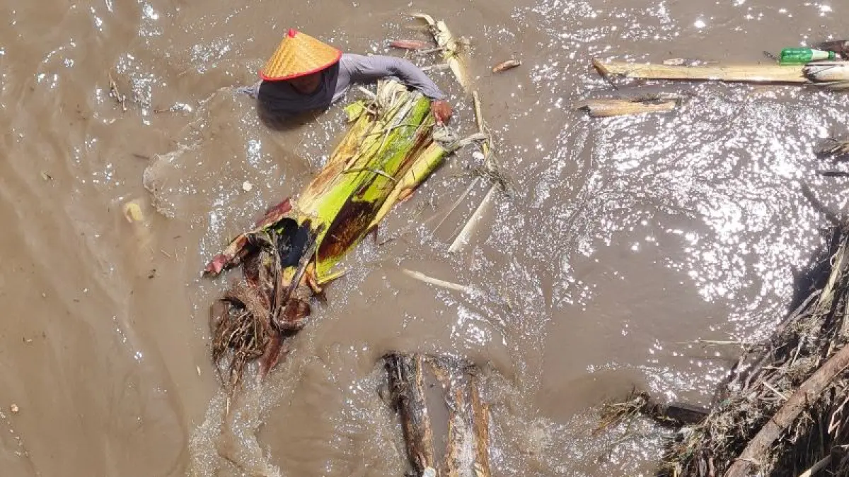 PROSES PEMBERSIHAN: Warga tampak membersihkan sampah dan material lahar yang menyumbat aliran air di Sabo Dam Srowol. (NAILA&nbsp;NIHAYAH/RADAR JOGJA)