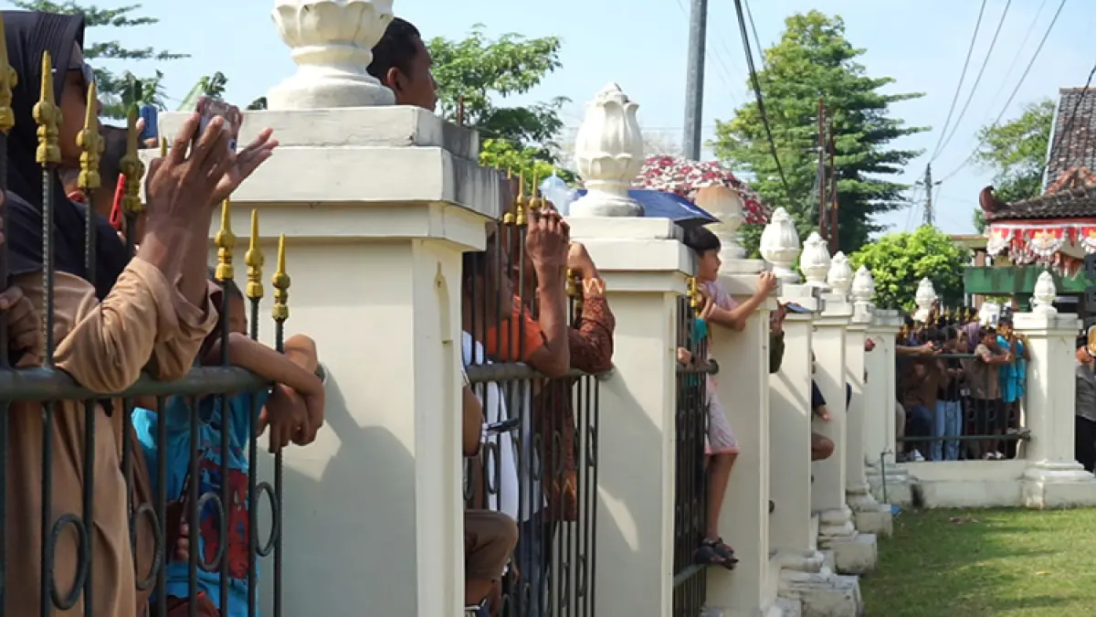 BERBATAS: Warga sekitar menonton upacara penghormatan dari balik pagar TMP Giripeni. (Anom Bagaskoro/Radar Jogja)