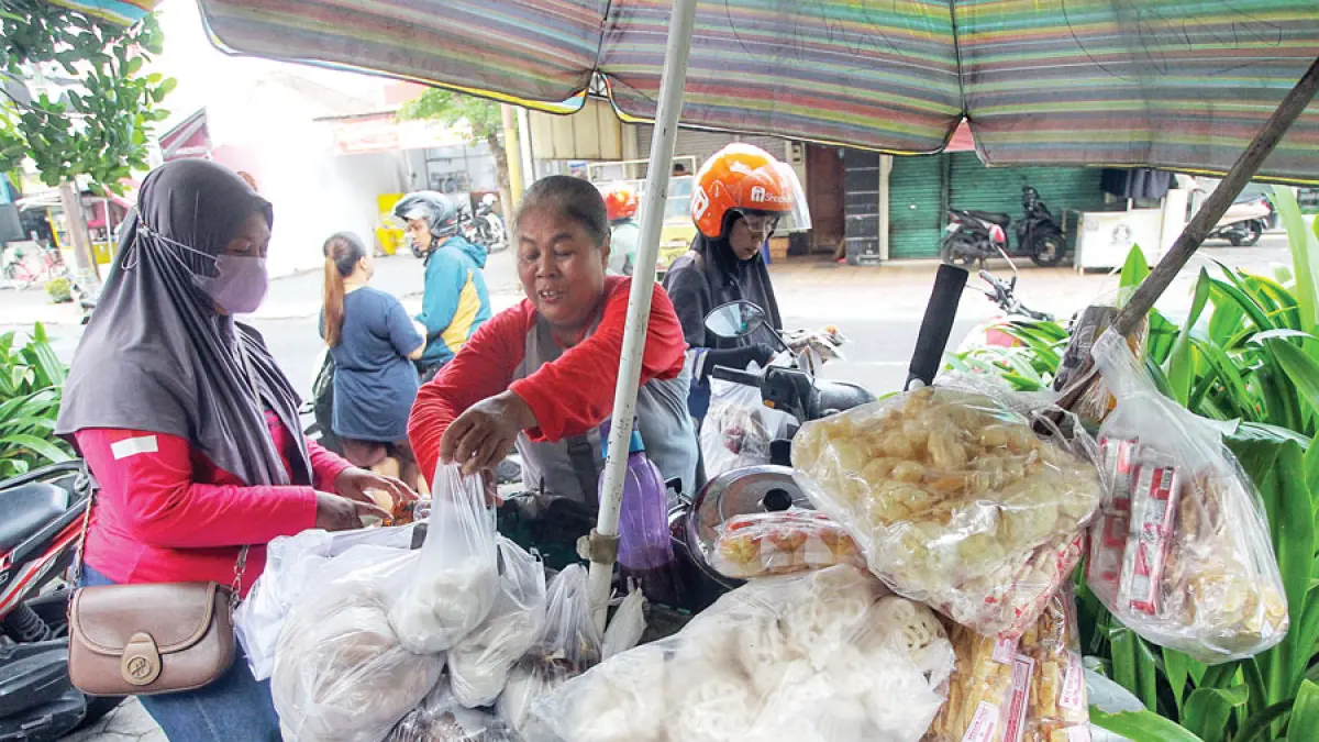 Penjual jajanan keliling mengemas dagangannya menggunakan kantong plastik di Jalan DI Panjaitan, Jogja, kemarin (6/4). Meroketnya harga plastik kian membebani pelaku usaha kecil. Guntur Aga Tirtana/Radar Jogja