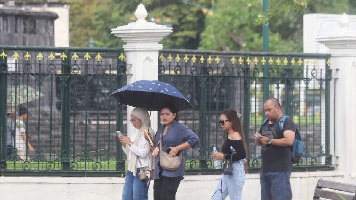 PANCAROBA: Seorang wisatawan menggunakan payung untuk melindungi diri dari terik matahari saat melintas di kawasan Titik Nol Kilometer, Kota Jogja Minggu (12/4). (Guntur Aga Tirtana/Radar Jogja)