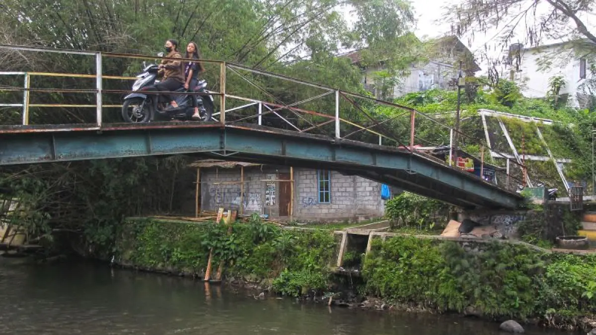 PERLU DITATA: Warga melintas di jembatan yang membentang di atas Sungai Winongo, Bener, Kemantren Tegalrejo, Kota Jogja Selasa (14/4). Sampai saat ini masih terdapat 41,50 hektare kawasan kumuh yang tersebar di sembilan kemantren. (Guntur Aga Tirtana/Radar Jogja)
