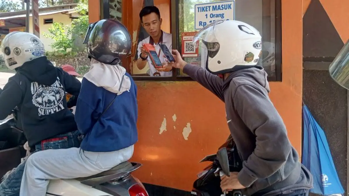 UJI COBA: Petugas retribusi TPR Baron sedang melayani pengunjung menggunakan transaksi nontunai Rabu (6/5). (Yusuf Bastiar/Radar Jogja)