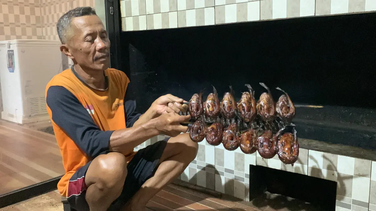 Suami Sumarsih memeriksa kondisi bara api agar lele matang sempurna. (ANOM BAGASKORO/RADAR JOGJA)&nbsp;