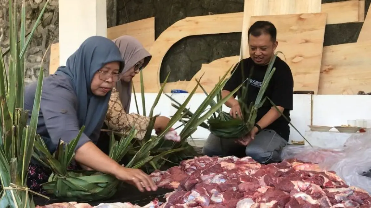 BUNGKUS: Warga Padukuhan Kopat memotong daging dan memasukkan ke dalam wadah daun kelapa atau dekon di Idul Adha 2025 lalu. (ANOM BAGASKORO/RADAR JOGJA)