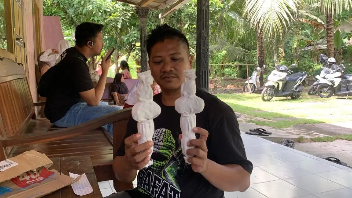 BONEKA: Sujarwo menunjukkan isi paket berisi mainan berbentuk pocong. (ANOM BAGASKORO/RADAR JOGJA)
