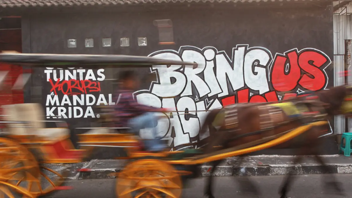 Pengguna jalan melintas di dekat mural bertuliskan “Usut Tuntas Korupsi Mandala Krida. Bring Us Back Home”, di Jalan Kemasan, kawasan Kotagede, Kota Jogja, Senin (1/6/2026).&nbsp;(Guntur Aga/Radar Jogja)