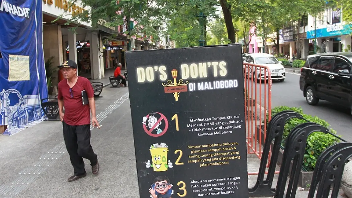 Pejalan kaki melintas di dekat papan informasi yang salah satunya berisi larangan merokok di kawasan Malioboro, Kota Jogja, Kamis (18/6/2026). Foto : Guntur Aga Tirtana/Radar Jogja 