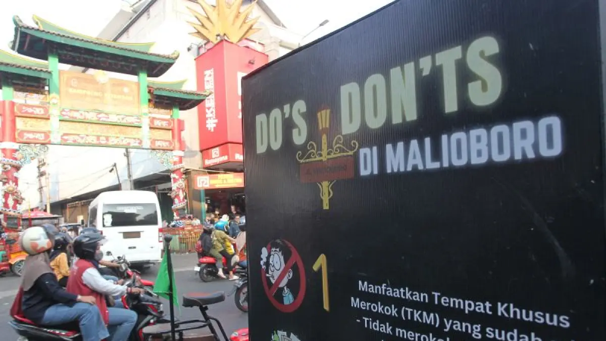Pejalan kaki melintas di dekat papan informasi yang salah satunya memuat larangan merokok di kawasan Malioboro, Kota Jogja, Minggu (5/7/2026). Foto: Guntur Aga Tirtana/Radar Jogja