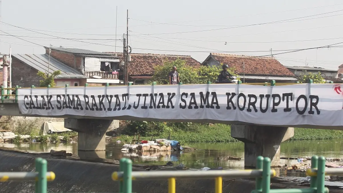 AMBISI: Warga melintas di jembatan Bendung Mergangsan yang dipasangi spanduk berisi aspirasi suporter terkait kasus hukum Stadion Mandala Krida, Senin (13/7/2026). GUNTUR AGA TIRTANA/RADAR JOGJA