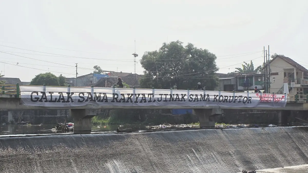 Warga melintas di jembatan Bendung Mergangsan yang dipasangi spanduk berisi aspirasi suporter terkait kasus hukum Stadion Mandala Krida, Kota Jogja, Senin (13/7/2026). Foto: Guntur Aga Tirtana/Radar Jogja