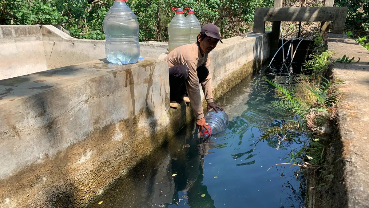 Seorang warga mengisi galon di Sumber Air Mendolo, Kalurahan Purwodadi, Kapanewon Tepus, Gunungkidul, Kamis (30/7). Warga rela menempuh sekitar tiga kilometer untuk mendapatkan air bersih. (Foto Dzika Fajar)

‎