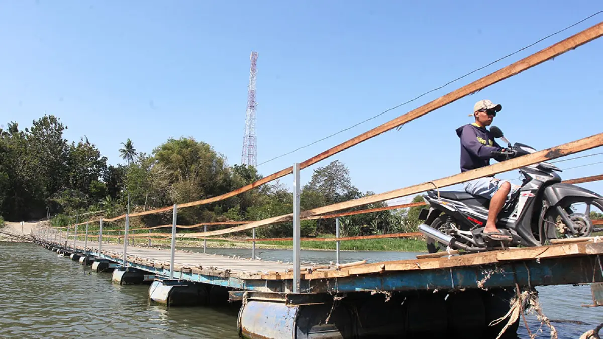 Pengendara kendaraan bermotor melintasi jembatan apung di atas Sungai Progo di Temben, Kalurahan Ngentakrejo, Kapanewon Lendah, Kulon Progo, kemarin (5/8). Jembatan apung tersebut mempermudah mobilitas warga Kulon Progo dan Bantul yang hendak menyeberangi Sungai Progo. Guntur Aga Tirtana/Radar Jogja&nbsp;