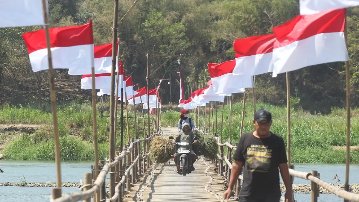 SIAP MELINTAS: Warga melewati&nbsp; Jembatan Sesek Temben yang dihiasi ratusan bendera Merah Putih di Ngentakrejo, Kapanewon Lendah, Kulon Progo, Rabu (5/8/2026). GUNTUR AGA TIRTANA/RADAR JOGJA