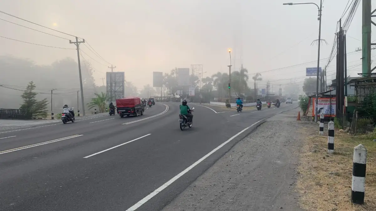 TEBAL: Pengendara sepeda motor berhenti di Simpang Tiga Tugu Pensil dengan suasana penuh kabut - ANOM BAGASKORO/RADAR JOGJA