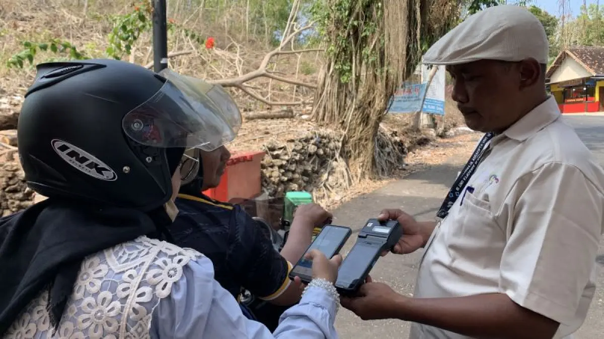 CASHLESS: Petugas TPR Pantai Baron membantu wisatawan melakukan pembayaran retribusi secara non-tunai. (Dzika Fajar/Radar Jogja)