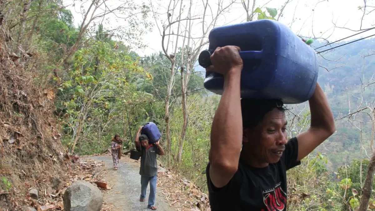 Warga Padukuhan Banaran, Kalurahan Pendoworejo, Kapanewon Girimulyo, Kulon Progo, rela berjalan kaki dua hingga lima kilometer melewati medan terjal Perbukitan Menoreh untuk mendapatkan air yang dibawa menggunakan jeriken, Rabu (19/8). (Guntur Aga Tirtana/Radar Jogja)