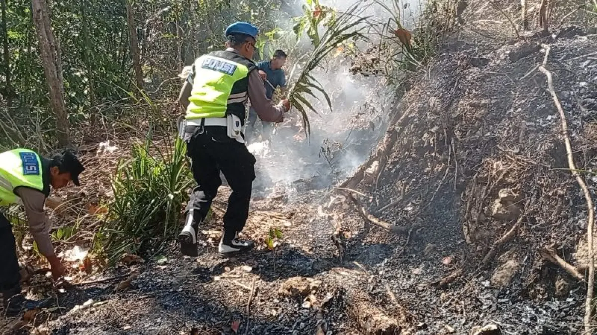 PEMADAMAN: Personel Polsek Karanganyar bersama warga berjibaku memadamkan kebakaran lahan dengan peralatan seadanya. (Dokumentasi Polres Kebumen)