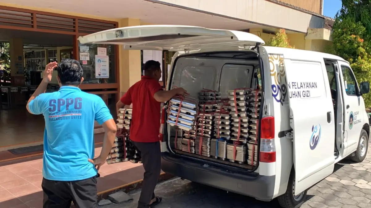 DISTRIBUSI: Petugas SPPG mengangkut ompreng dari sekolah ke mobil penjemputan. (ANOM BAGASKORO/RADAR JOGJA)