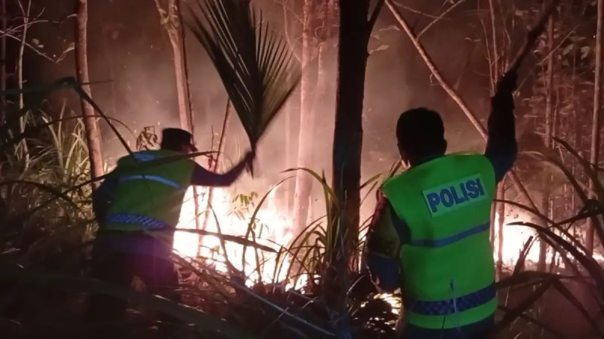 PENANGANAN: Petugas melakukan pemadaman api di lahan milik Perhutani dengan menggunakan alat seadanya. (Dokumentasi Polres Kebumen)