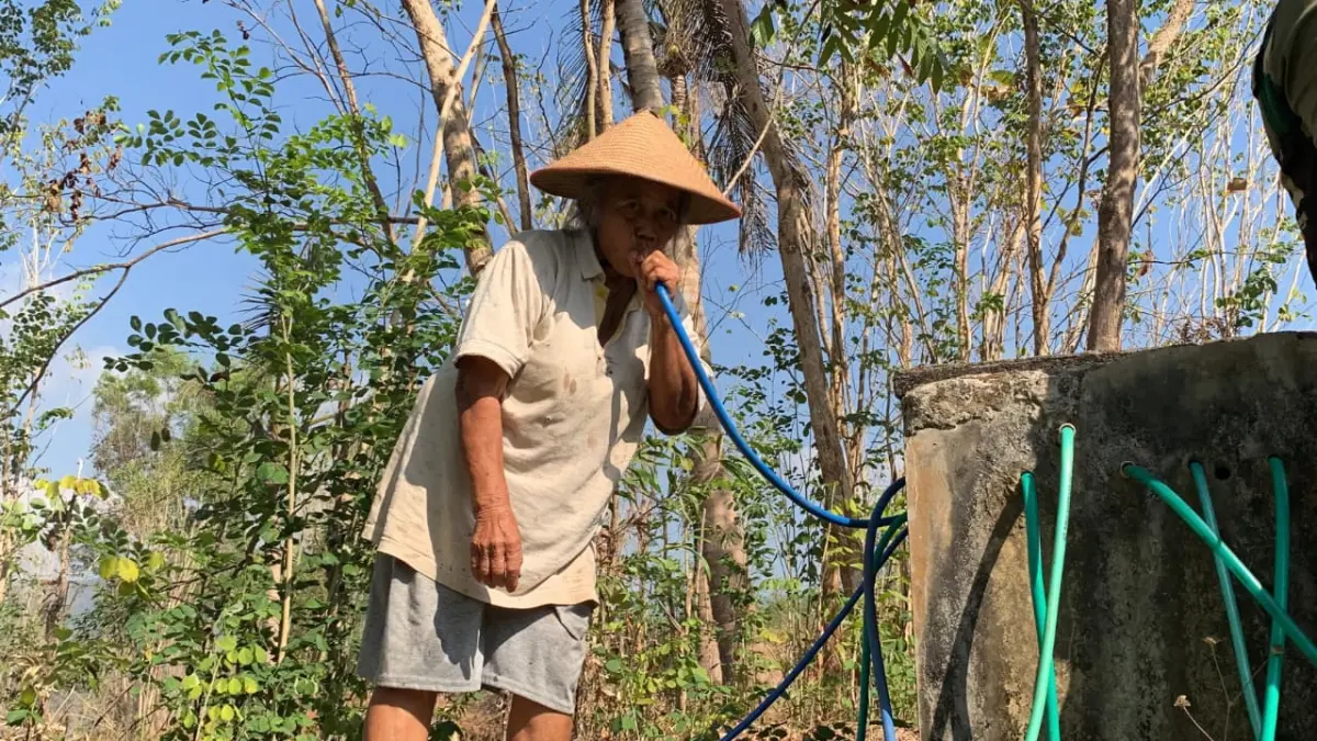 COBA: Salah satu Warga Padukuhan Kemaras menyedot selang dari bak penampungan air demi mencukupi kebutuhan. (ANOM BAGASKORO/RADAR JOGJA)