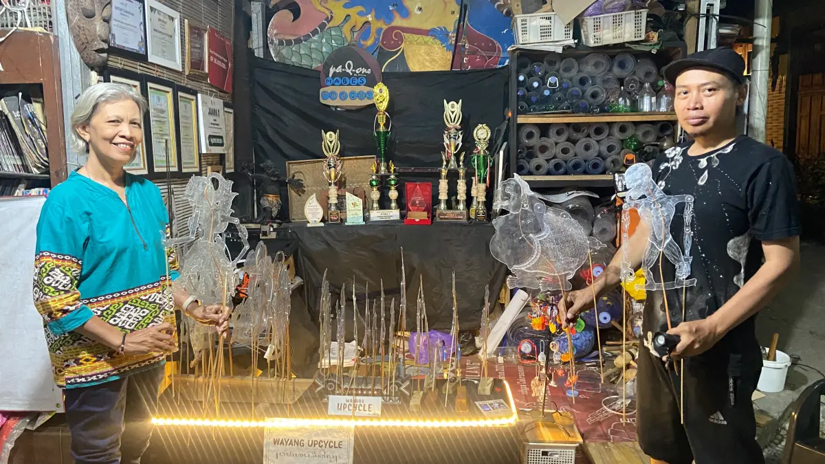 Seksi Pengembangan Wayang Upcycle Pak Q One Budi Anggoro sedang memegang wayang berbahan dasar plastik