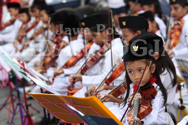 RAYAKAN KEMERDEKAAN: Anak-anak anggota Sanggar Biola Quinta memainkan alat musik biola mengiringi lagu-lagu perjuangan di kawasan Titik Nol Kilometer, Jogjakarta, Selasa (16/8). (GUNTUR AGA TIRTANA/RADAR JOGJA)