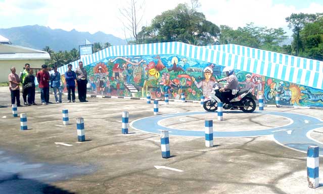 BERI CONTOH: Seorang anggota polisi memberikan contoh praktik ujian mengendarai motor sebagai syarat untuk mendapatkan Surat Izin Mengemudi (SIM) di Kompleks Satlantas Polres Magelang.(Foto:  ADIDAYA PERDANA/RADAR JOGJA)
