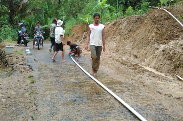 SIRAM AIR : Masyarakat dan relawan membersihkan sisa-sisa tanah di jalan paska longsor di Desa Kalirejo, Salaman.